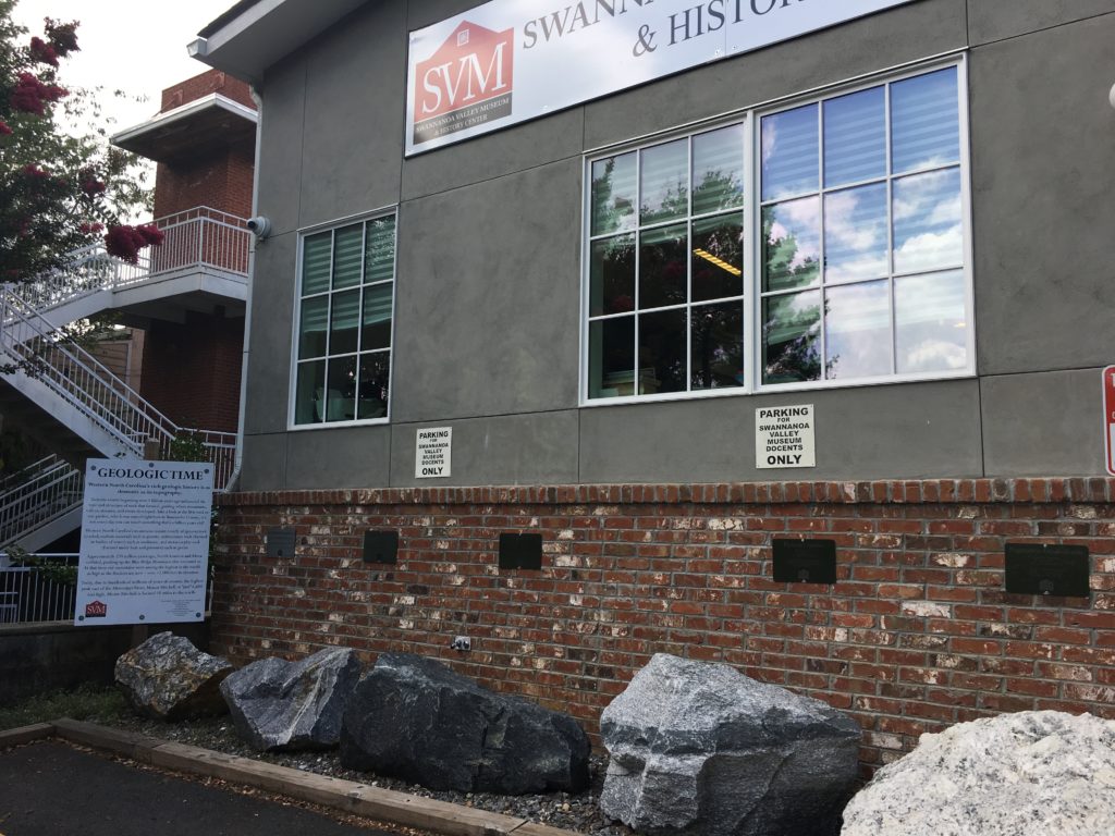 Photograph of a geology exhibit with six rocks behind the Swannanoa Valley Museum.